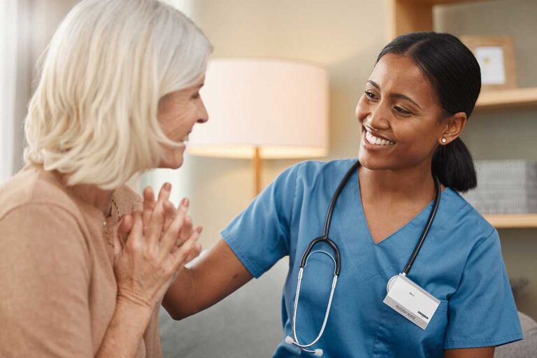 Older adult and family member reviewing care options at a table with a nurse in a bright residential setting.